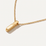 Gold necklace with a rectangular pendant on a light background