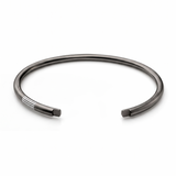 Black rhodium open cuff with parallel white enamel groove details near one end.