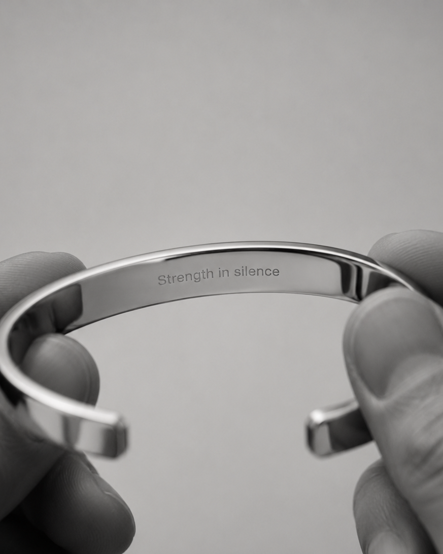 A close-up of a polished silver cuff bracelet held between two hands, with the engraved words 'strength in alliance' visible on the inside. The image is in grayscale and includes the word 'personalization' at the bottom.
