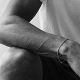 Black and white close-up of a person's arm with a bracelet, wearing a t-shirt.