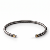 Black rhodium open cuff with twin gold-tone line details at each end and engraved somethingaboutus logo.